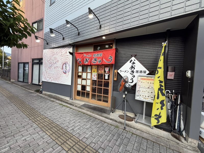 なおきゅうの外観。赤い暖簾に「ラーメン居酒屋 なおきゅう」、白い袖看板が出ています