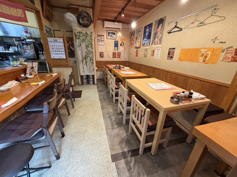 なおきゅうの店内。テーブル席が並び、壁にポスターが貼られています